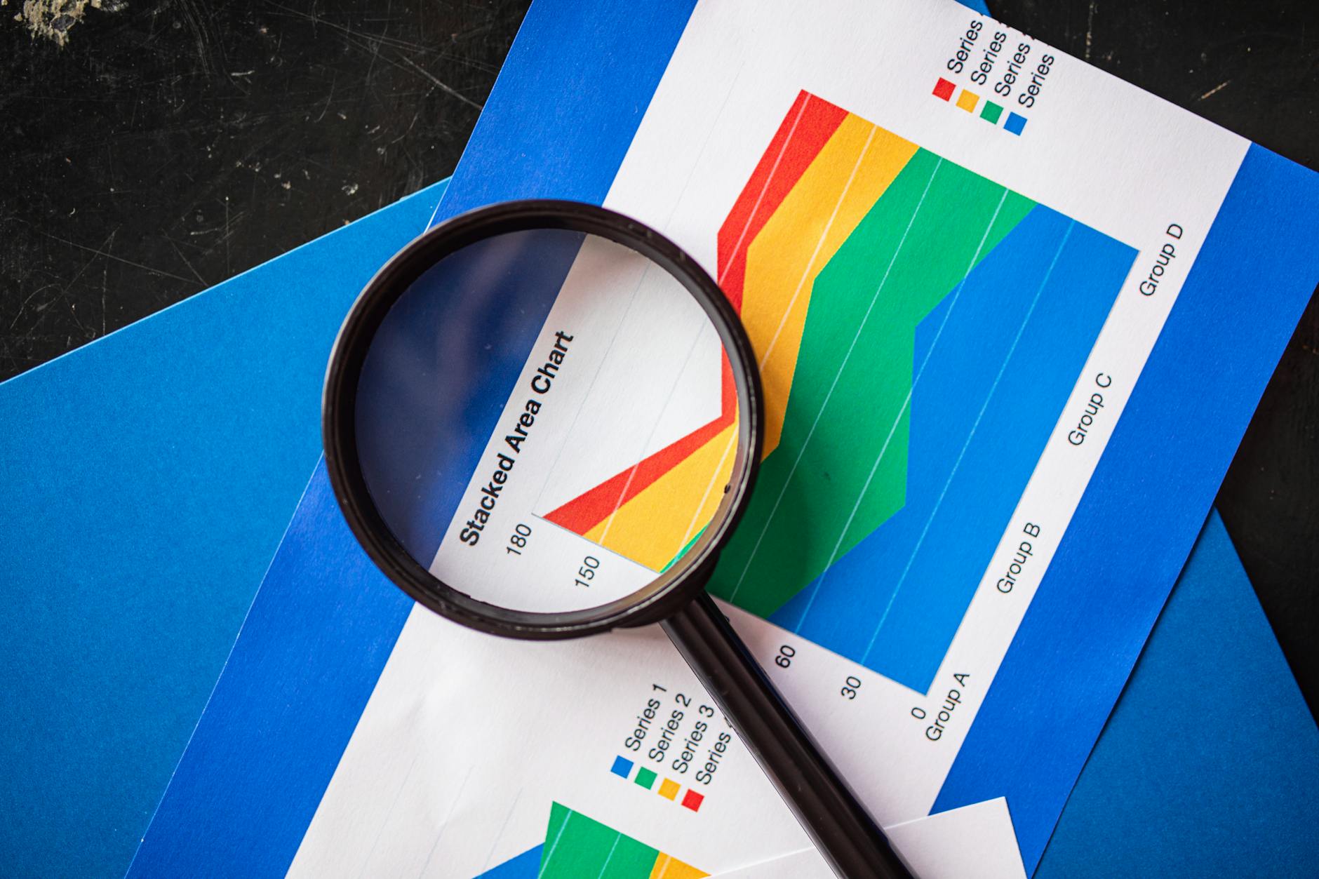 Top 4 Auto Stocks to Buy After May Sales Data: Maruti to Escorts 2 Magnifying glass highlighting stacked area charts for business analysis. - Top 4 Auto Stocks to Buy After May Sales Data: Maruti to Escorts